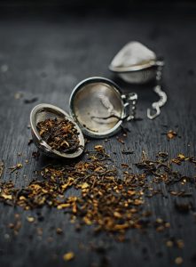 Stainless steel tea infuser with loose leaf tea on dark background